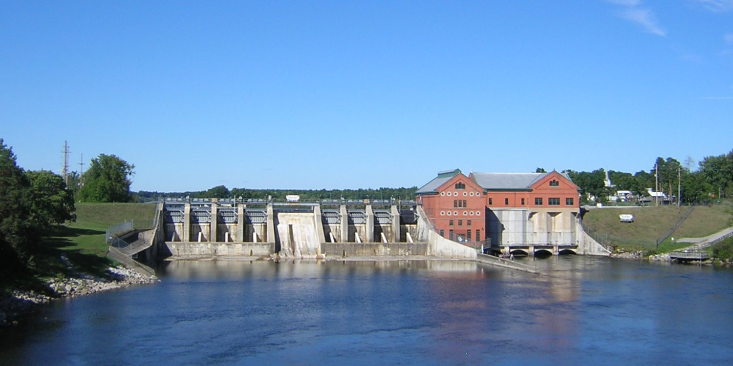Croton Dam on the Muskegon River in Michigan, with flowing water and greenery, symbolizing Iron Fortress LLC’s vision for sustainable hydroelectric-powered Bitcoin mining and AI innovation